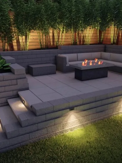 This is a closer look at a modern backyard design featuring a cozy seating area with a fire pit. The multi-level hardscaping with built-in lighting creates a sophisticated ambiance, perfect for evening gatherings.