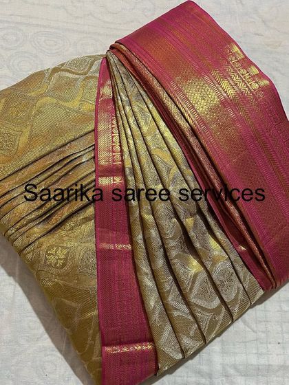 A beautiful gold and pink silk saree, folded to protect its delicate weave and keep it ready for the next event.