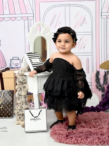 A little fashionista in the making. This chic setup features a Parisian boutique backdrop and designer shopping bags for a stylish and glamorous first birthday shoot.