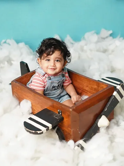 A full shot of the little pilot in his wooden plane, surrounded by fluffy clouds. This theme is perfect for capturing a child's sense of adventure.