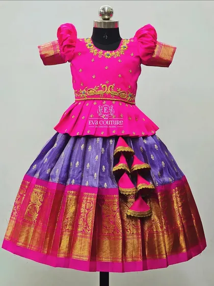A classic pink and purple Pattu Pavadai. The blouse has simple gold embroidery, and the skirt has a traditional gold border.