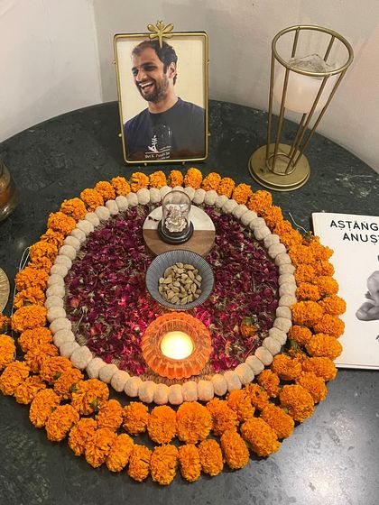 A sacred corner of our shala, with a photo of my Guru, an Ashtanga manual, and offerings of flowers and light. This space holds the intention and reverence for our practice.