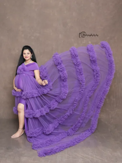 A full-length shot showcasing the dramatic train of a purple ruffled gown in our studio. The flying fabric creates a sense of movement and elegance.