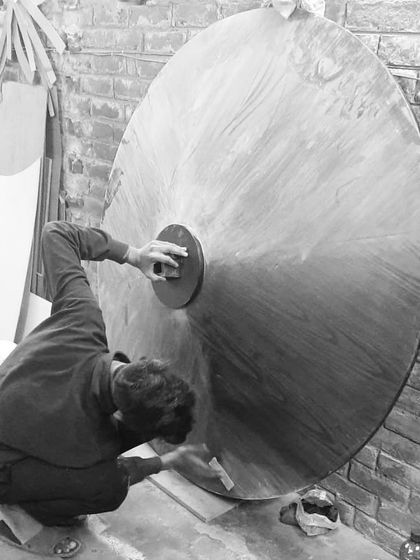 One of our craftsmen performing the final sanding and polishing on the large dining tabletop. This meticulous process ensures a perfectly smooth and durable finish before it heads to its new home.