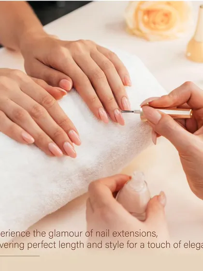 The art of application. A sheer, natural pink polish is carefully brushed onto beautifully shaped nails, creating a look of understated elegance.