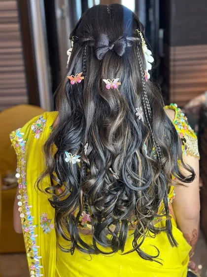 A fun and creative Haldi hairstyle with butterfly clips, small braids, and beachy waves.