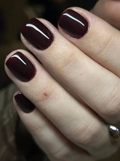 A deep, dark burgundy polish on short, natural nails. This sophisticated shade is timelessly chic.