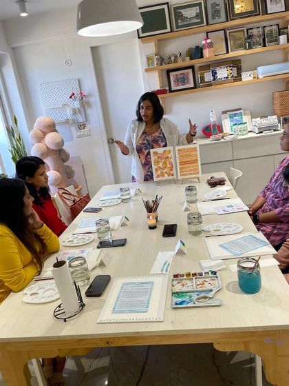 An instructor leads a watercolor workshop, explaining the techniques to an attentive group of participants.