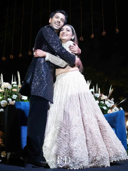 A candid moment of the happy couple at their Sangeet. The decor, with its soft florals and ambient lighting, provides a beautiful backdrop for their joy.