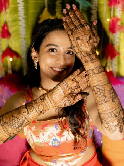 A happy portrait of the bride, her hands adorned with classic peacock and floral mehendi.