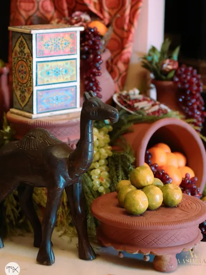 A decor vignette rich with local flavor, featuring a wooden camel figurine, fresh citrus fruits, and a hand-painted chest of drawers.