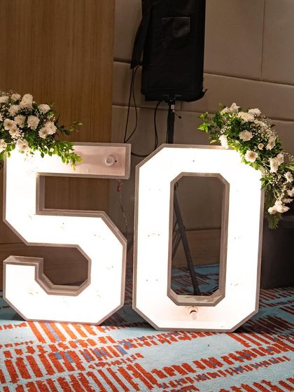 Large, light-up marquee numbers are a fantastic way to mark a milestone. For this 50th birthday, I adorned the numbers with simple white floral arrangements to add a touch of elegance.