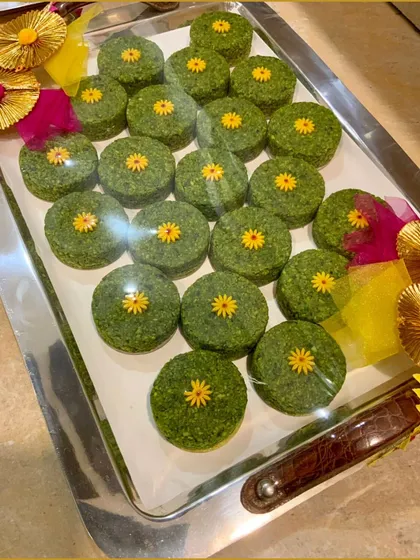 A close-up of our unique green sweets, decorated with tiny flowers. We offer a variety of artisanal mithai to make your wedding celebrations even more special.