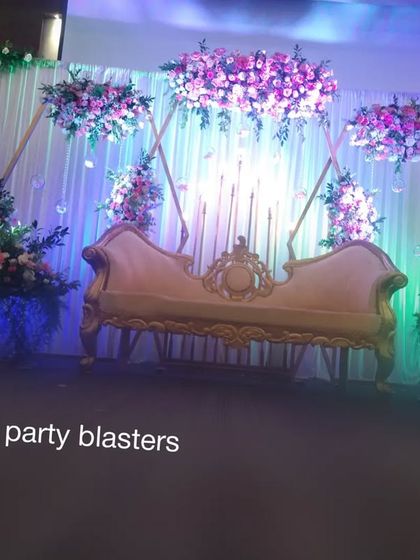 A wider angle of the anniversary stage, showing the full effect of the hanging floral structures and the dramatic uplighting.