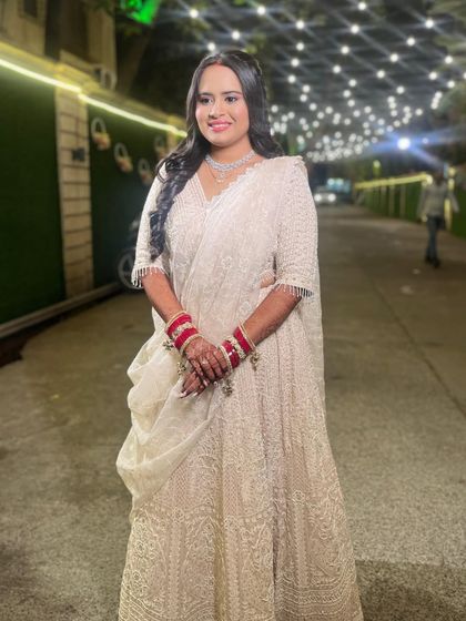 A full-length shot of the elegant white reception lehenga. The makeup is sophisticated, with a bold lip and defined eyes.