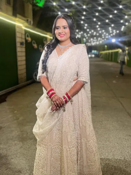The full view of this stunning white reception lehenga, complemented by soft, glowing makeup and classic red bangles.