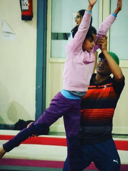 Practicing leaps on the beam. Our coaches provide support to help students master the balance and strength required for such moves.