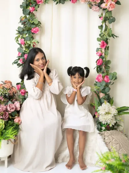 A fun, mirrored pose with a mother and daughter framing their faces with their hands, showing their playful connection.