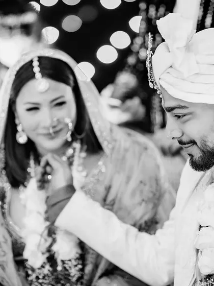 A candid black and white moment during Sahil and Aerie's ceremony. The groom's gentle touch captures a moment of quiet connection amidst the grandeur of the wedding rituals.