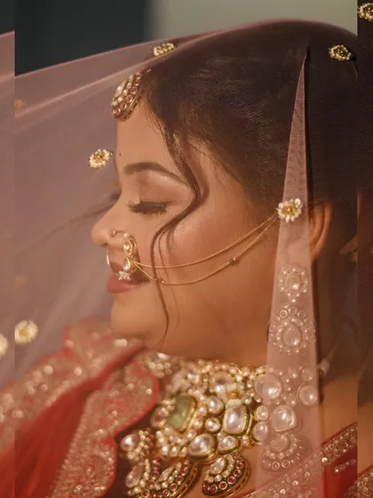 A dreamy profile shot of the bride with her veil. The soft lighting highlights her flawless makeup and the delicate chain of her nath.