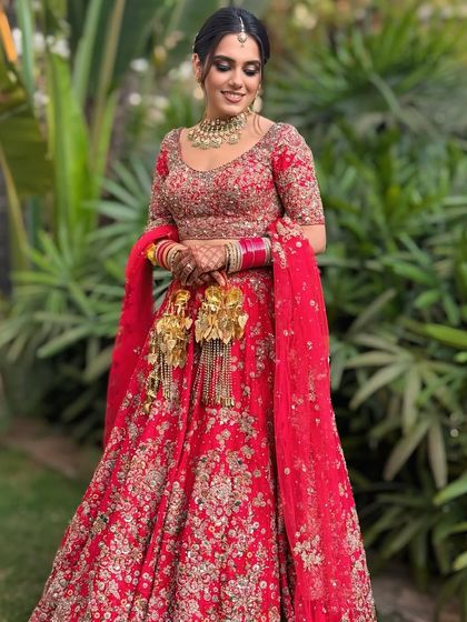 A stunning bride in her red lehenga, with her hair styled in a romantic floral updo. The soft tendrils and the placement of the flowers create a very dreamy and ethereal vibe.