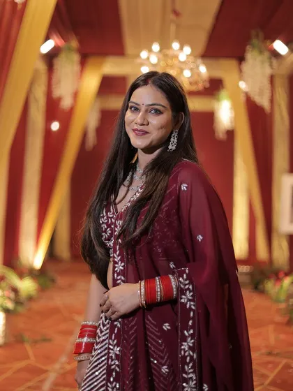 A smiling portrait of the client in her festive maroon lehenga.