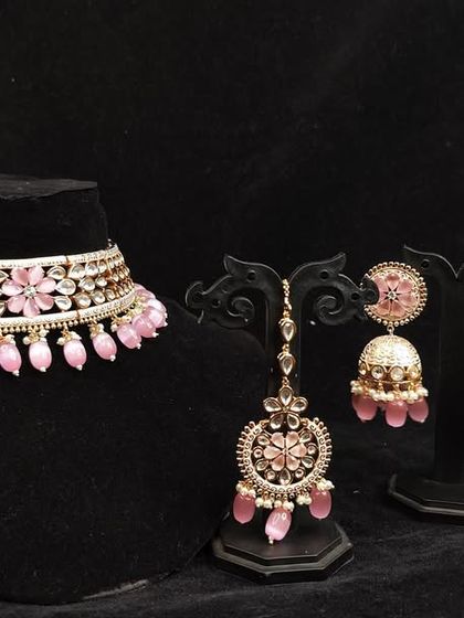 A complete choker set with matching earrings and maang tikka in a lovely pastel pink, available to rent for a coordinated look.