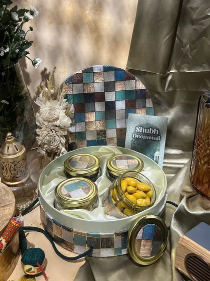 A round box with a colorful mosaic-patterned lid. This is a fun and artistic choice for packing Diwali sweets or dry fruits.