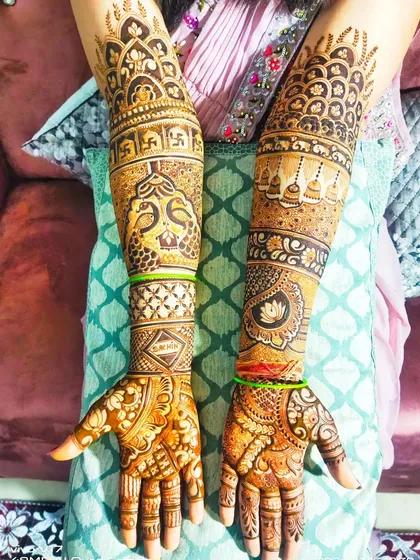 This full-arm design is rich with traditional symbols. It includes peacocks, swastikas, and hanging bells, all woven together with intricate jaali and floral patterns.