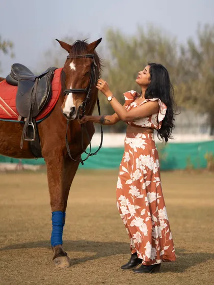 A full-length shot of a model adjusting the horse's bridle, a great candid moment for any equestrian-themed shoot.