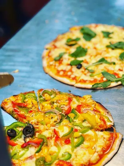A live pizza station in action, showing our freshly baked pizzas with assorted toppings, a guaranteed crowd-pleaser at any event.
