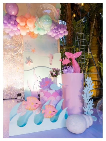 A close-up of our mermaid-themed decor, featuring a pink mermaid tail, cute fish cutouts, and a large seashell, all set against a backdrop of pastel waves.