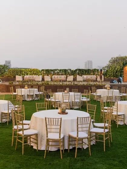 The full layout of the lawn reception, with round tables elegantly set for guests and a beautifully lit stage in the background.