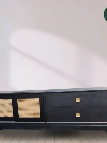 This modern console table features a black finish with woven cane sliding doors and simple brass knobs. It's a beautiful blend of modern design and natural textures.