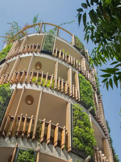 A low-angle view of the Outré House, emphasizing the verticality of the planters and the texture of the turned wooden louvres that wrap around the building.