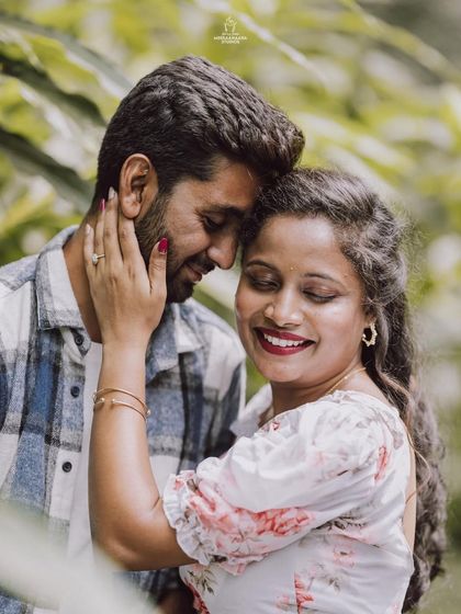 A single, beautiful portrait from a pre-wedding shoot, capturing the couple's close bond amidst a natural, green setting.