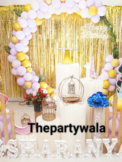 A princess theme with a shiny gold foil curtain backdrop. The mix of pastel purple and yellow balloons with Jasmine and Aurora cutouts makes for a bright and cheerful party.