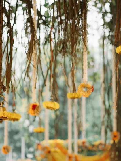 A close-up of the charming, rustic details in my tree decor. Small floral hangings and traditional bells are suspended from the banyan roots, adding small touches of beauty to the overall design.