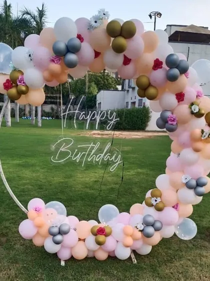 A beautiful pastel balloon ring for an outdoor birthday party. This delicate arrangement with small floral accents is perfect for a garden or park celebration.