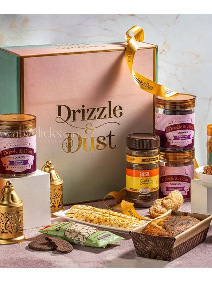 A premium gift box from Drizzle & Dust, elegantly styled with cookies, cakes, and decorative candles.