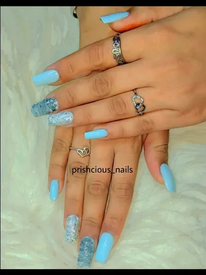Nails are like jewels. This set proves it with a beautiful sky blue, silver glitter, and a blue marble accent nail.
