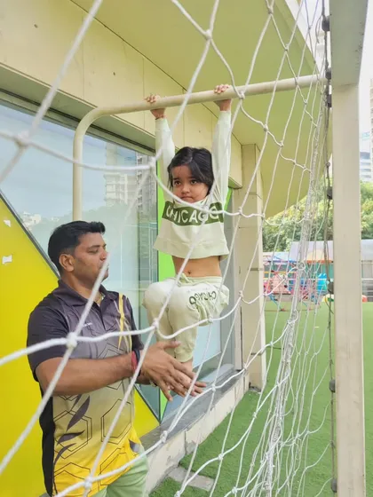 A young girl tests her strength and coordination on the climbing net, carefully supported by her coach. Our summer camp activities are designed to challenge students and help them overcome physical hurdles.