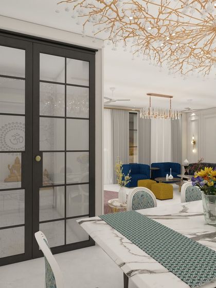 A view from the dining area into the living room in our Villa 72 project design. The glass doors for the mandir add to the open and connected feel of the space.