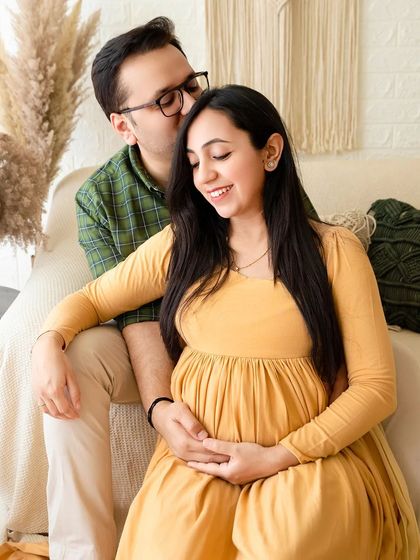 A sweet and candid moment between expecting parents during their boho-style studio shoot. The warm color palette and comfortable setting make for a relaxed and authentic portrait.