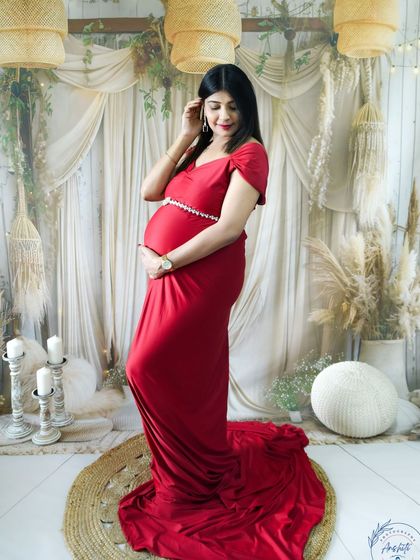A graceful portrait in our boho-chic studio. The mom-to-be is wearing a simple yet elegant red gown, creating a timeless and romantic look.
