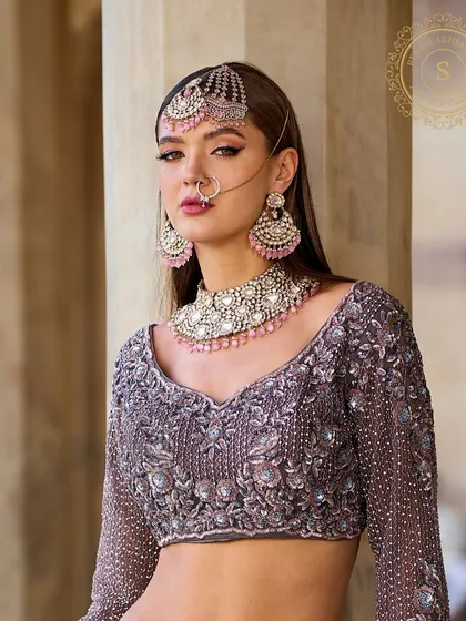 How can the groom take his eyes off a bride as beautiful as her jewellery? This model pairs a stunning grey-lavender lehenga with a matching pink stone jewellery set.