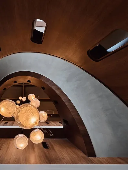 Looking up from the bottom of the staircase, this perspective offers a dramatic view of the architectural curves and the cluster of lights, creating an almost abstract composition of form and light.