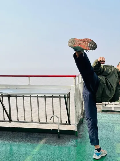Practicing a high kick on a ferry. Discipline means you can train anywhere, focusing on flexibility and control even in unconventional environments.