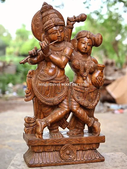 This 20-inch sculpture of Radha and Krishna captures a moment of divine love. Carved with a rich wax brown finish, the piece highlights the intricate details of their adornments and the emotion shared between them, perfect for home altars.