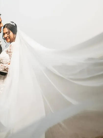 A tender moment with the groom kissing his bride's forehead, her veil sweeping across the frame. This shot is all about quiet affection and romance.